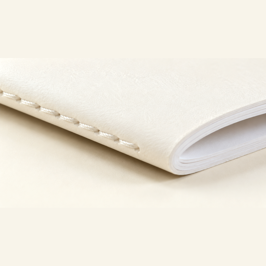 Dos cousu d'un carnet à la couture Singer, fil blanc apparent